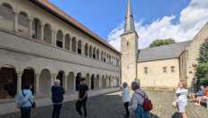 Gruppe von Touristen betrachtet die Architektur eines Klosters mit einem Kirchturm
