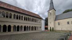 Ein Innenhof mit einem mittelalterlichen Gebäude mit Arkaden und einem Kirchturm.