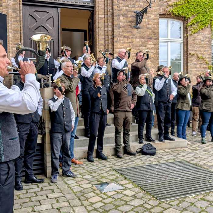 Eine Gruppe von Menschen spielt Blasinstrumente vor einem Gebäude.